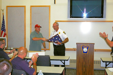 At his last Roll Call before retiring, Lt Dorman accepts a US Flag